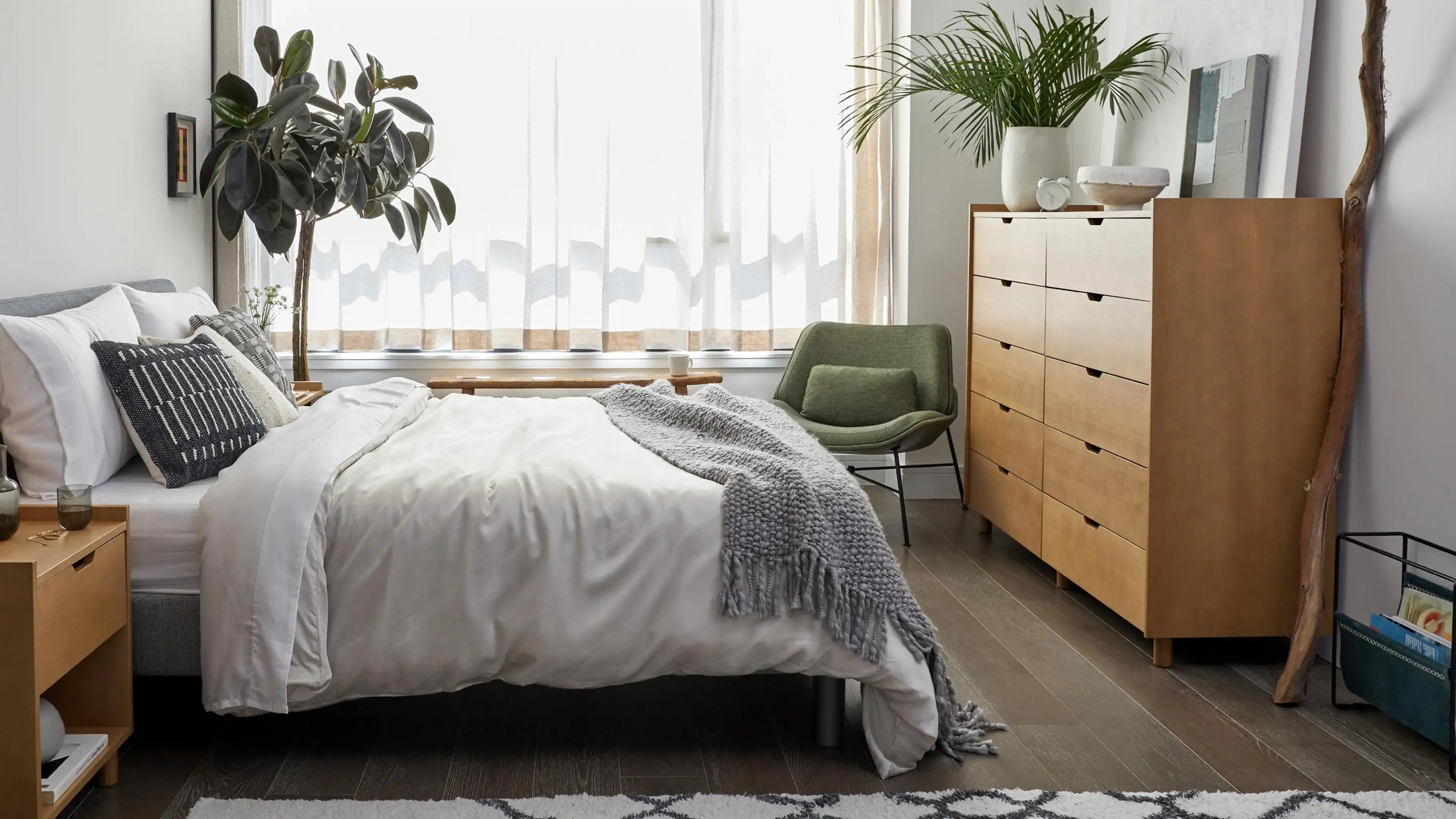 a bedroom with a bed, dresser, and plants