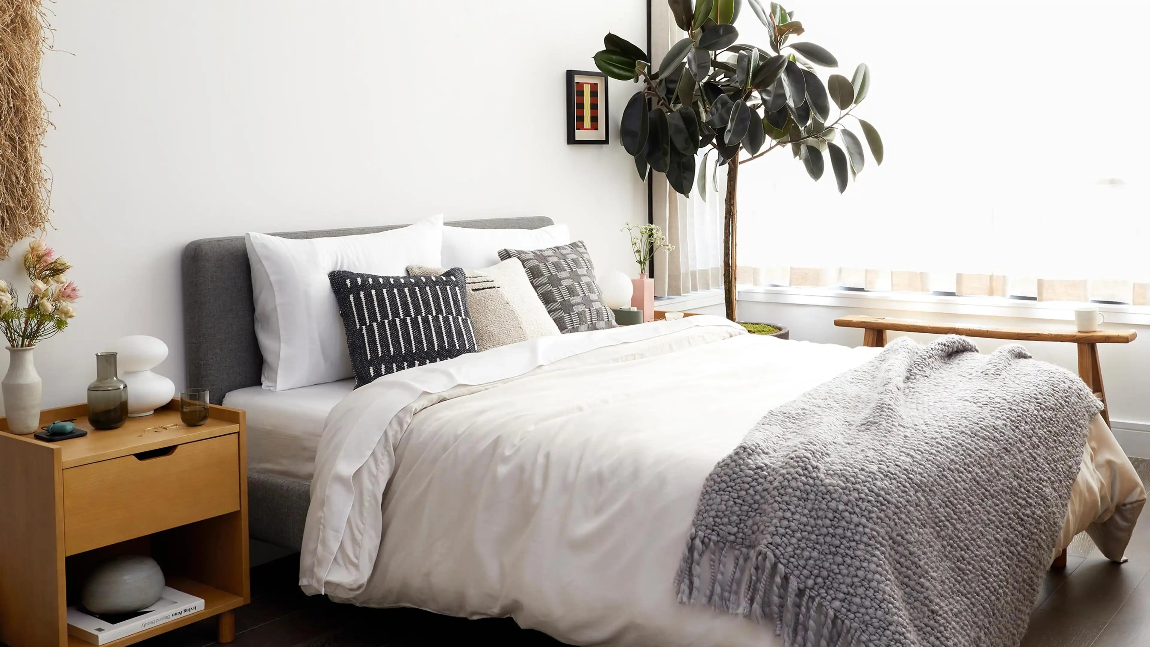 a bedroom with a bed, nightstand, and plant