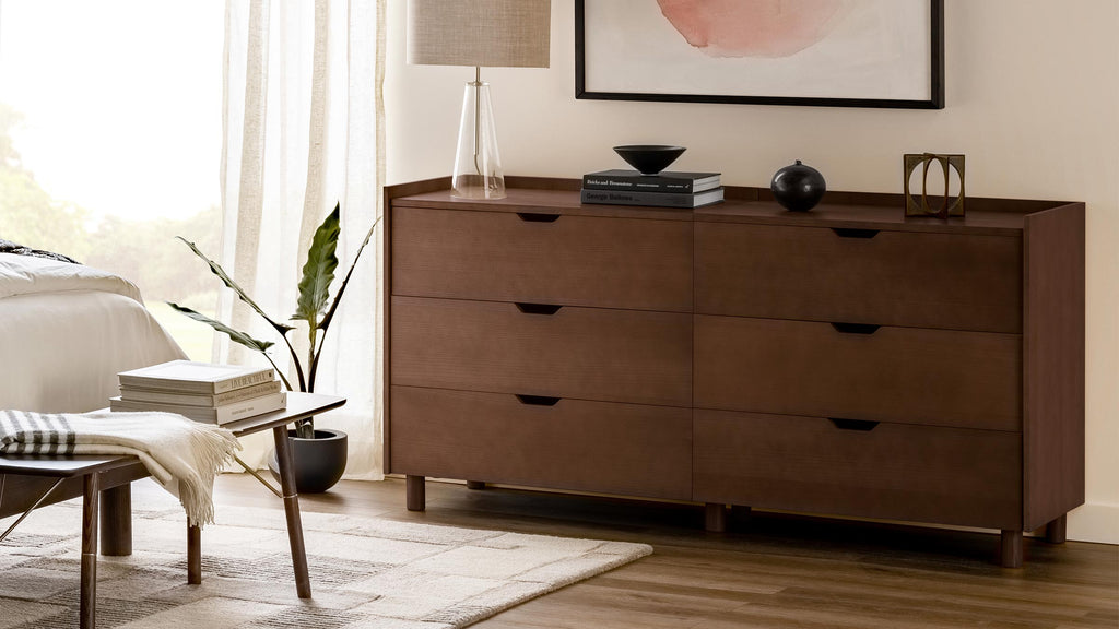 Modern wooden dresser with six drawers, dark brown finish, styled with a lamp, books, decorative items in a cozy bedroom.