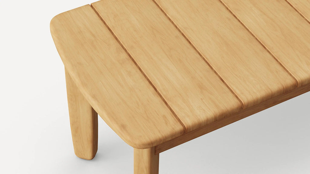 Close-up of a light wood rectangular table corner with three slatted planks and rounded edges and legs.