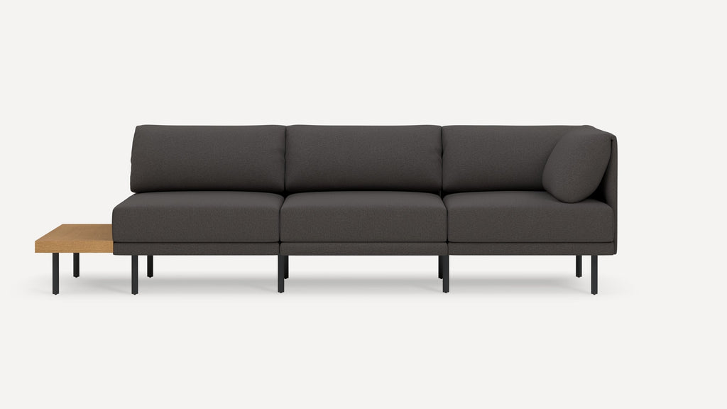 Modern dark gray fabric three-seater sofa with black metal legs and an attached light wood side table on the left.