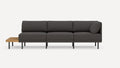 Modern dark gray fabric three-seater sofa with black metal legs and an attached light wood side table on the left.