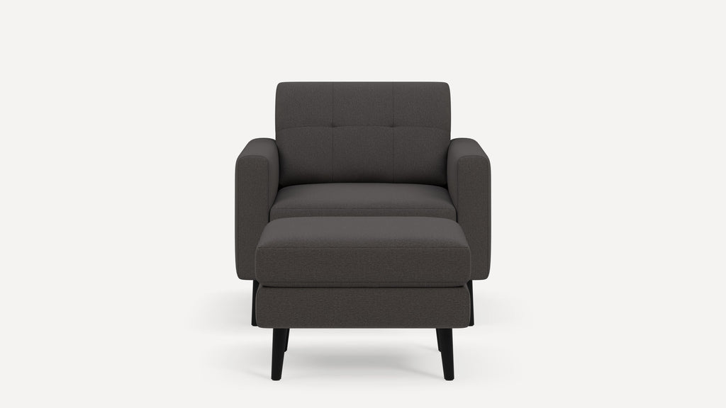 Front view of a modern dark gray fabric armchair with a cushioned seat and backrest, supported by four black legs.