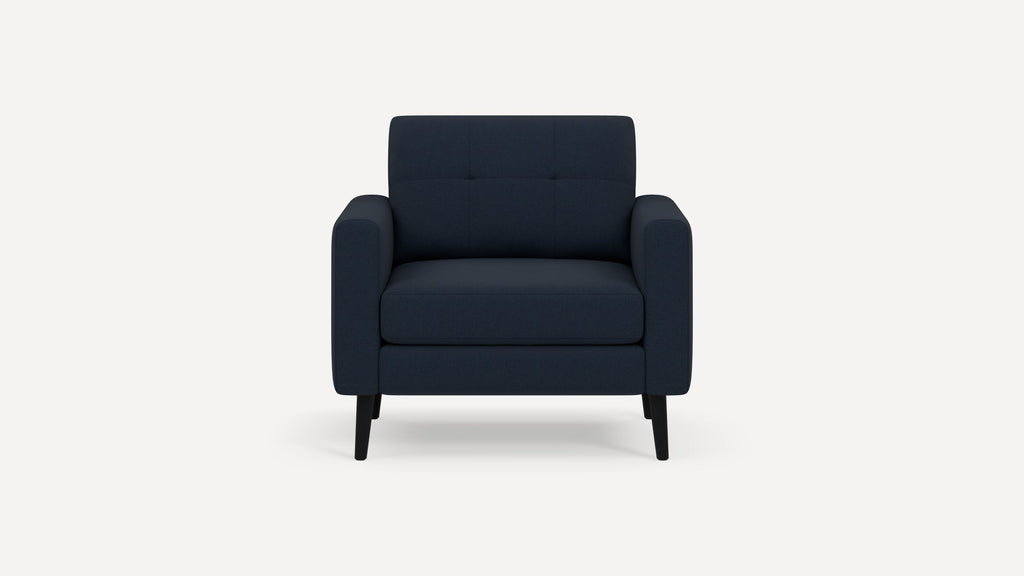 Modern navy blue upholstered armchair with tufted backrest, cushioned seat, and black wooden legs, front view.