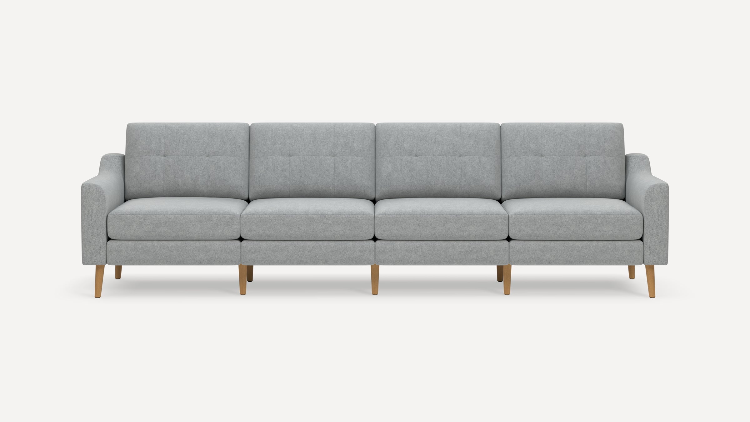 Modern light gray fabric four-seater sofa with tufted back cushions and wooden legs, against a plain white background.