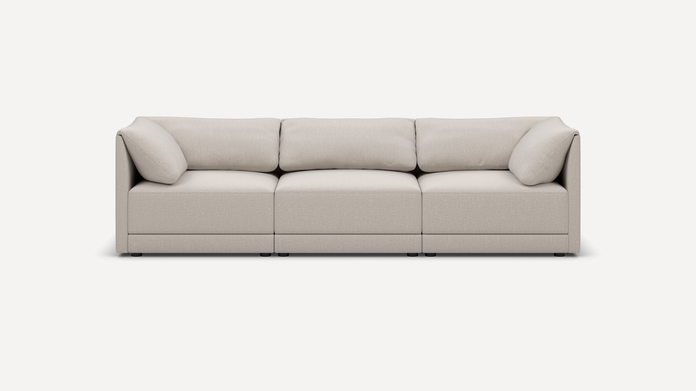 Light beige three-seater modern sofa with clean lines, plush cushions, and low black legs on a white background.