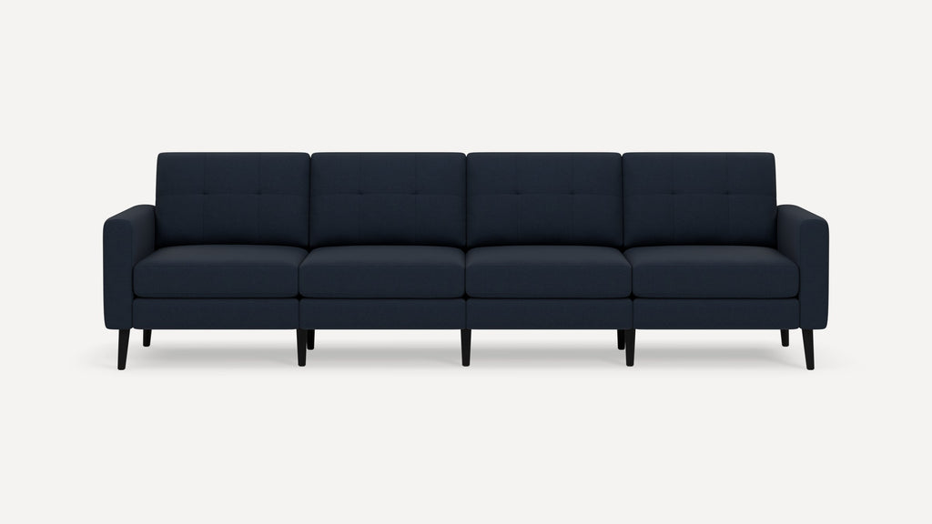 Modern navy blue four-seater sofa with tufted cushions and slim black wooden legs, shown against a plain white background.