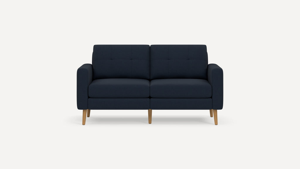 Dark blue modern two-seater sofa with tufted cushions and wooden legs on a plain white background.