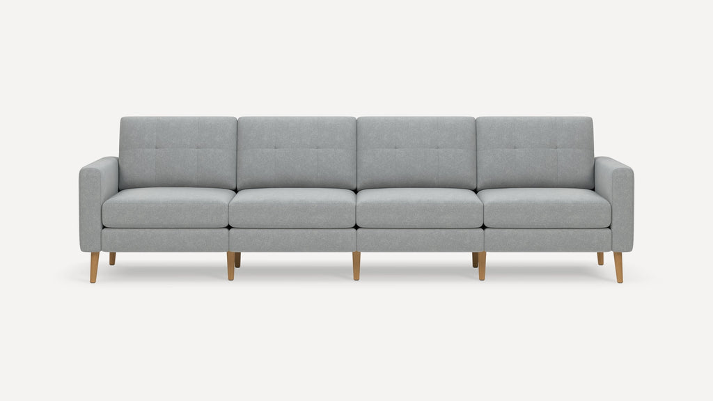 Modern four-seater sofa with light gray fabric upholstery, tufted back cushions, and wooden tapered legs.