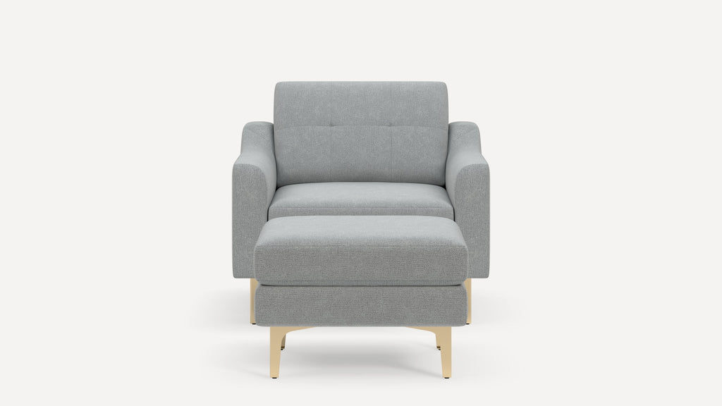 Front view of a modern light gray fabric armchair with a matching ottoman and light wood legs on a white background.