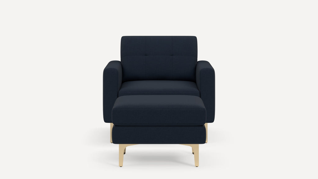 Modern dark blue upholstered armchair with matching ottoman and light wooden legs, shown on white background.