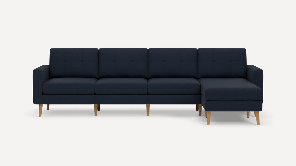 Modern navy blue sectional sofa with tufted back cushions and light wooden legs, featuring a right-side chaise lounge.