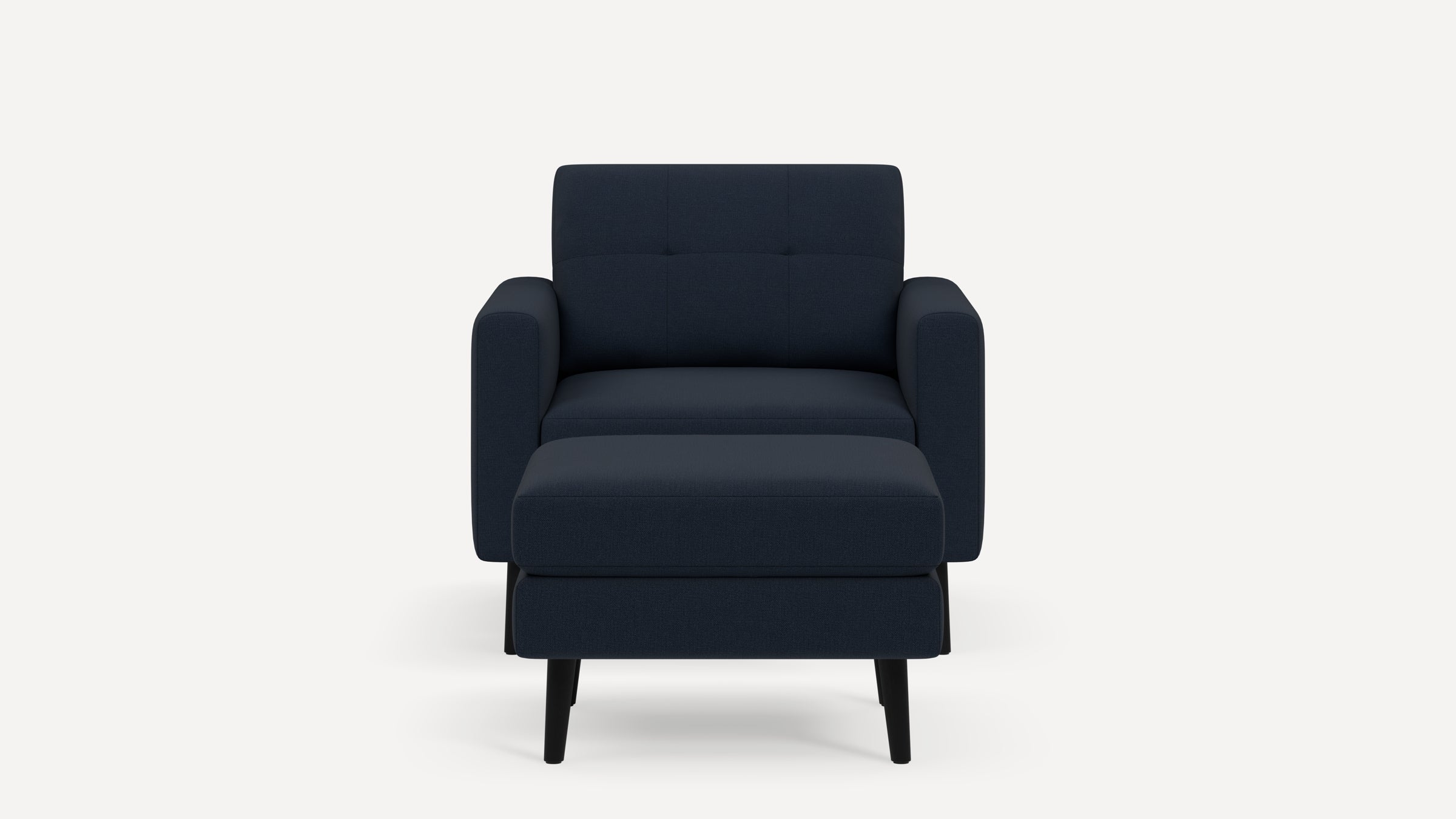 Front view of a modern dark blue armchair with tufted backrest and matching ottoman on black tapered legs.