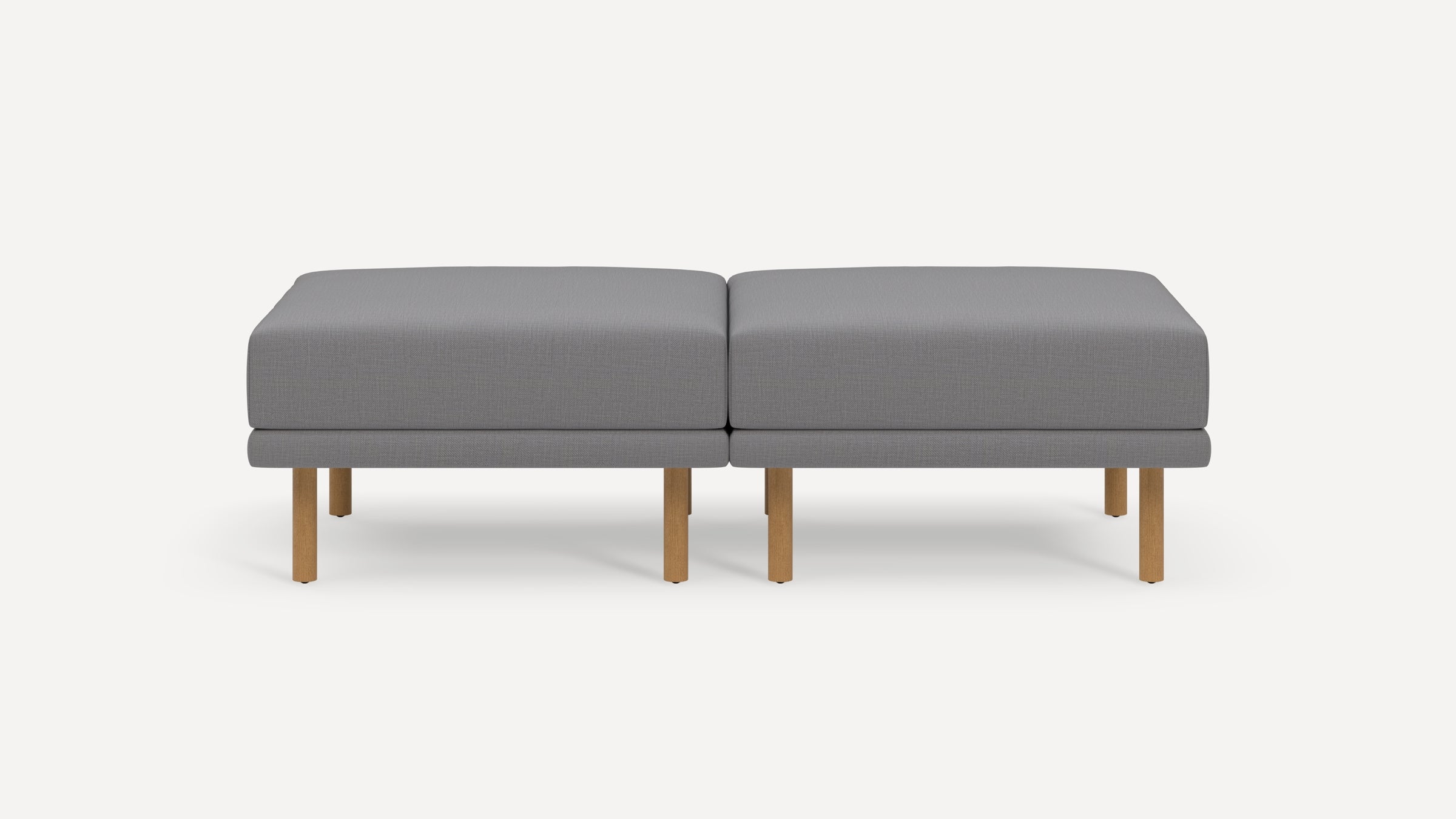 Modern gray upholstered bench with wooden legs, featuring two connected cushioned seats and clean, minimalist design.