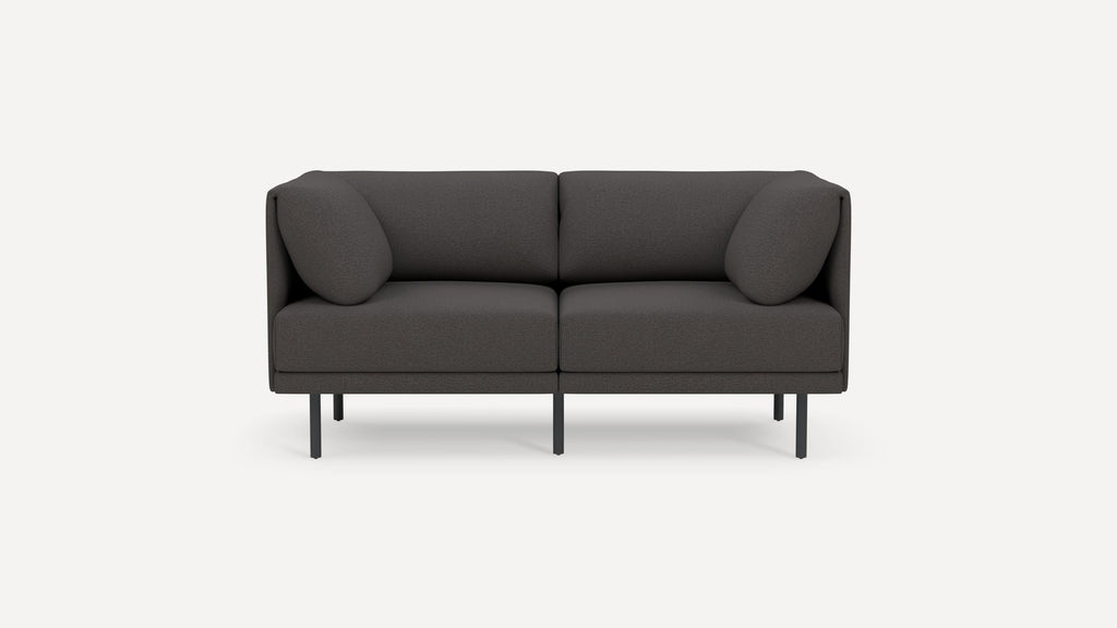 Modern dark gray two-seater sofa with rounded cushions and slim black metal legs, shown on a plain white background.