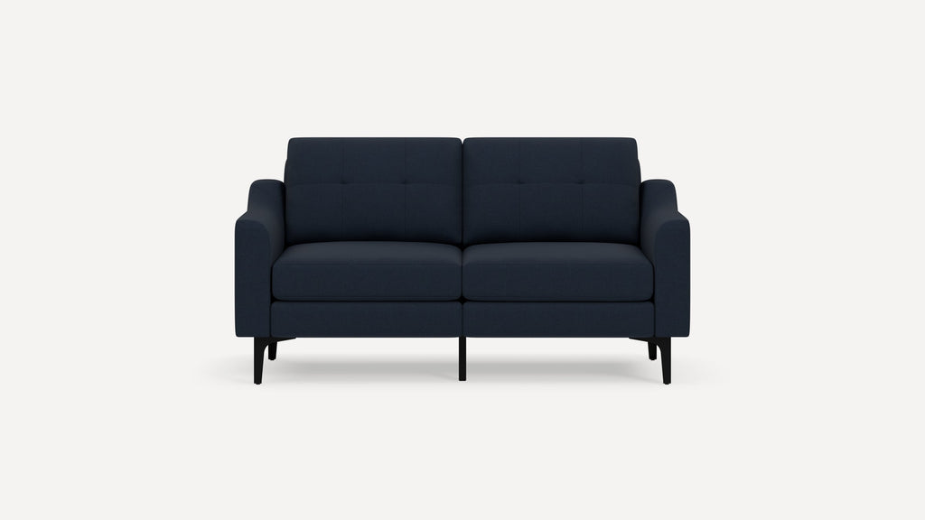 Dark blue modern two-seater sofa with tufted back cushions, slim black legs, and gently curved armrests on a white background.