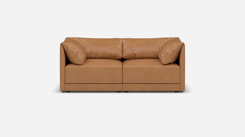 Front view of a modern, tan leather two-seater sofa with plush cushions and low armrests on a white background.