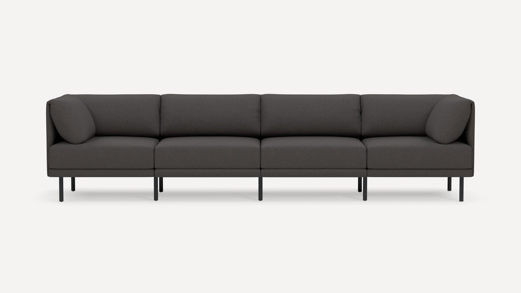 Modern dark gray four-seater sofa with clean lines, upholstered cushions, rounded armrests, and slim black legs on white background.