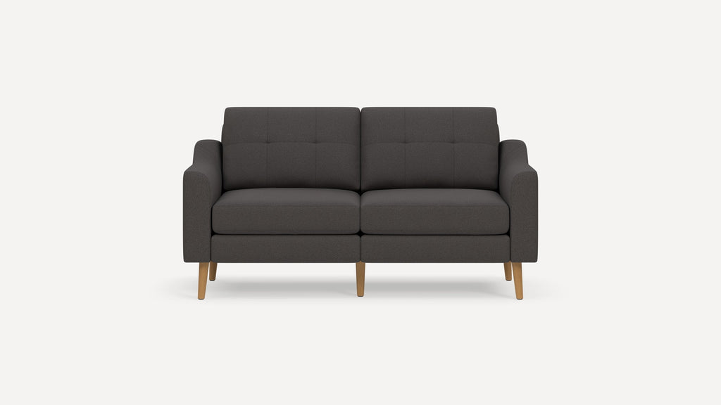 Dark gray modern two-seater sofa with wooden legs and tufted back cushions, against a plain white background.