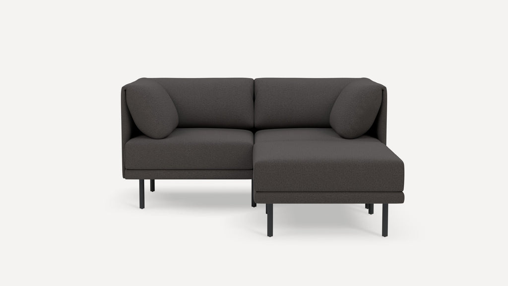 Dark gray modern sectional sofa with metal legs, cushioned backrests, and two round pillows, minimalist design.