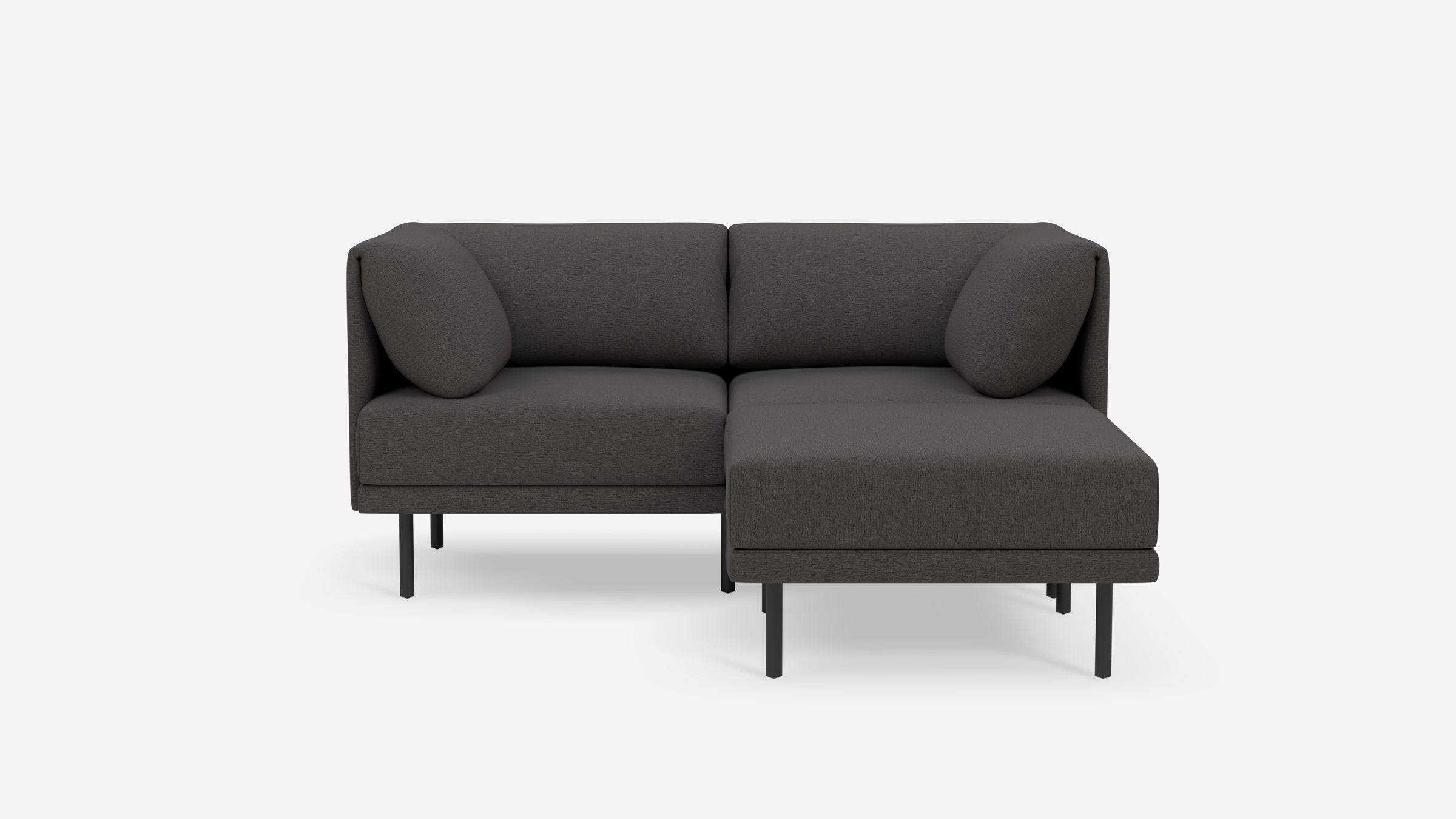 Dark gray modern sectional sofa with metal legs, cushioned backrests, and two round pillows, minimalist design.