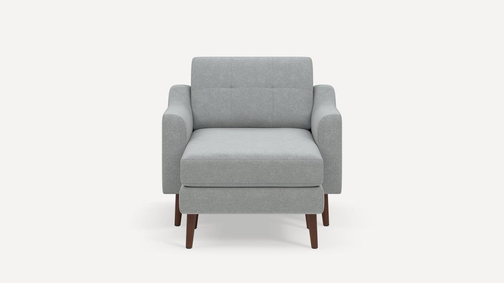 Modern light gray upholstered armchair with dark wooden legs, featuring a cushioned seat and backrest with subtle button tufting.