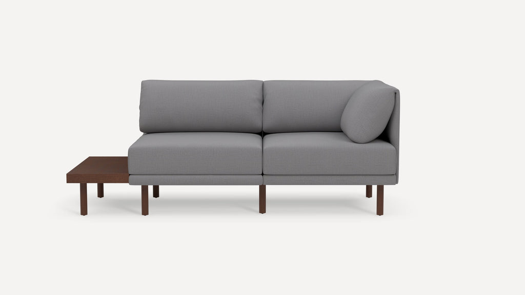 Modern gray two-seater sofa with wooden legs and attached wooden side table, featuring clean lines and minimalist design.