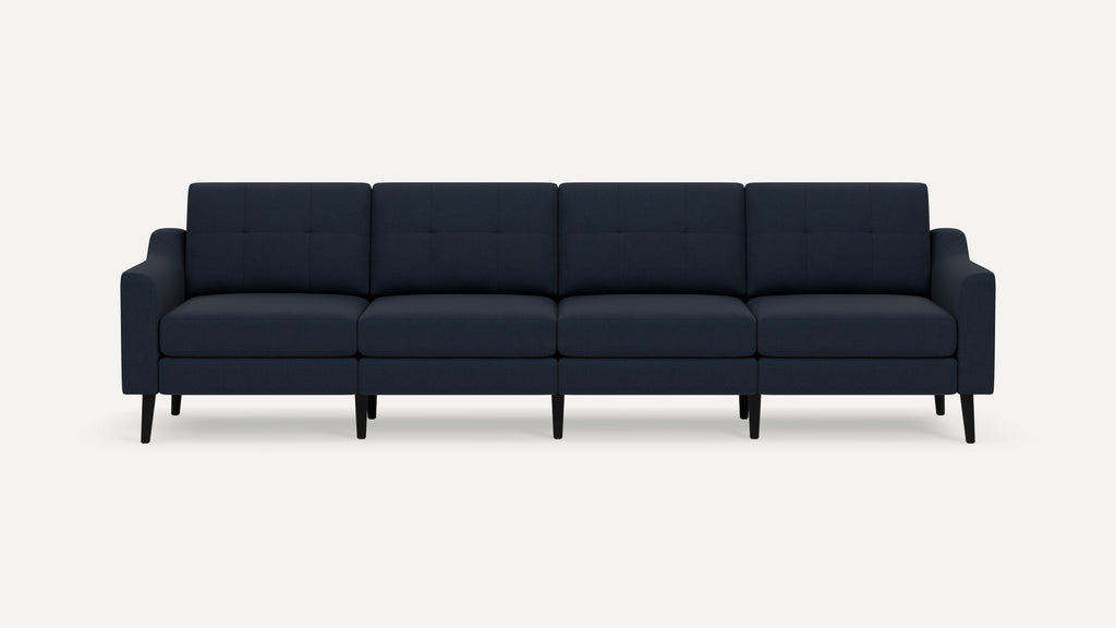 Modern navy blue four-seater sofa with tufted back cushions, slim armrests, and black tapered legs on a white background.