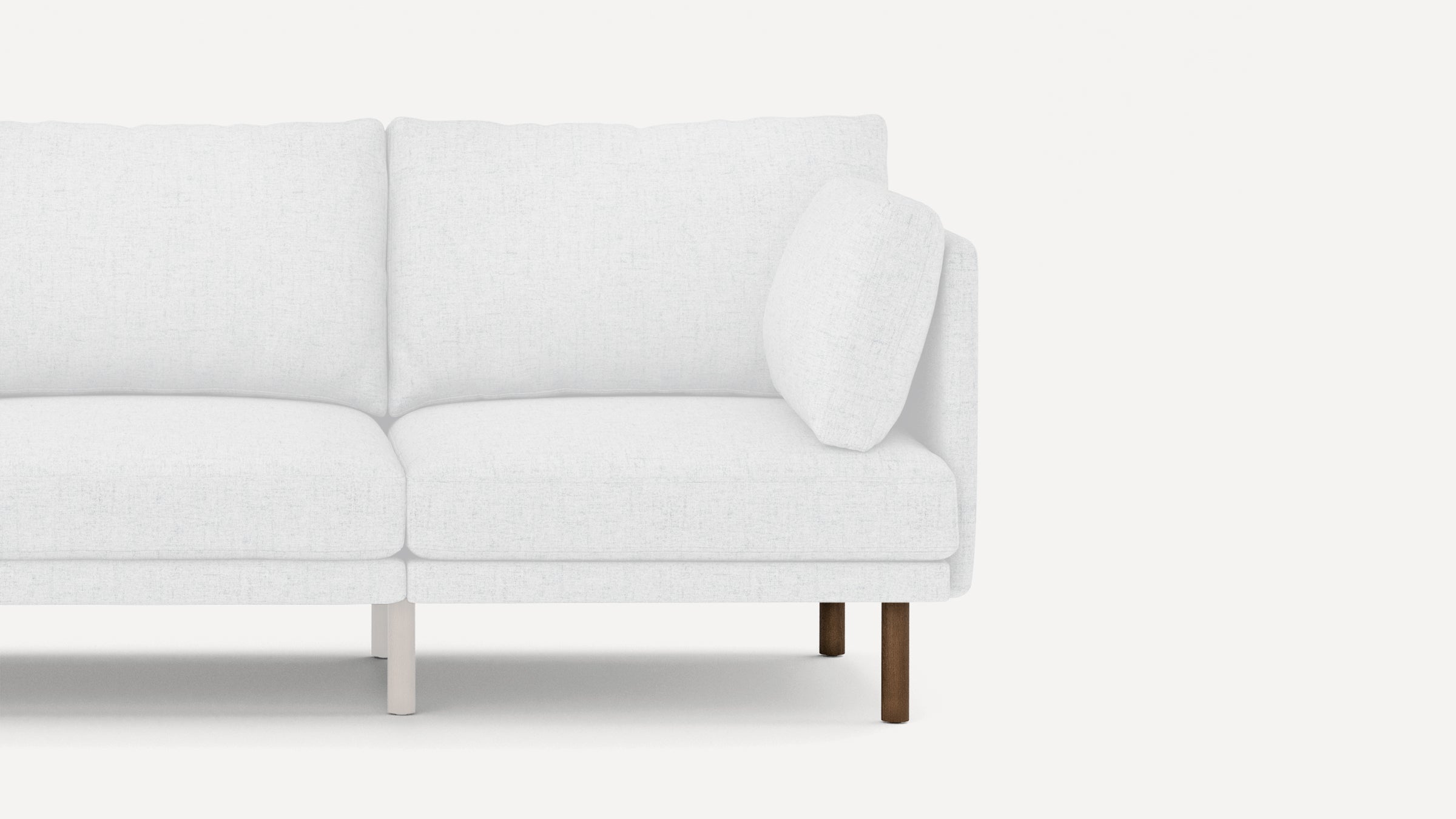 Modern white fabric sofa with cushioned seats, backrests, and a single matching pillow on wooden legs.