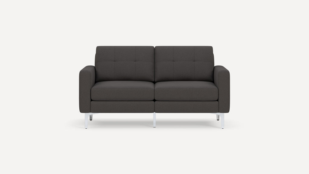 Modern dark gray two-seater sofa with tufted backrests, cushioned armrests, and sleek white metal legs on a plain background.