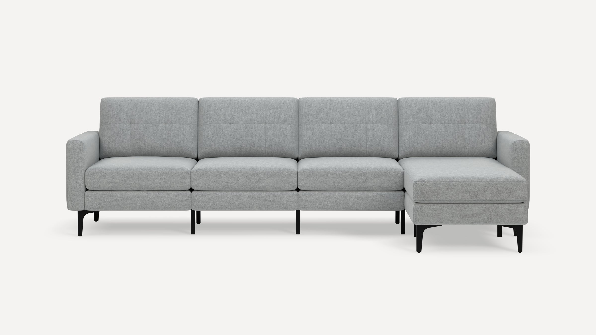 Modern gray fabric sectional sofa with chaise lounge on the right side, black legs, and tufted back cushions.