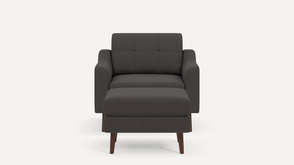 Front view of a dark gray upholstered armchair with matching ottoman and wooden legs on a plain background.