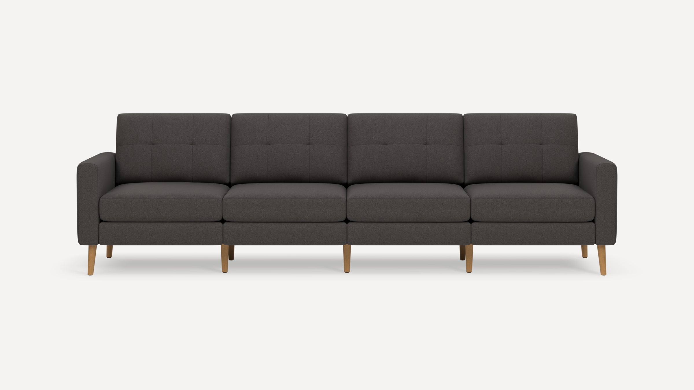 Four-seat dark gray upholstered sofa with tufted back cushions and light wooden tapered legs on a plain white background.