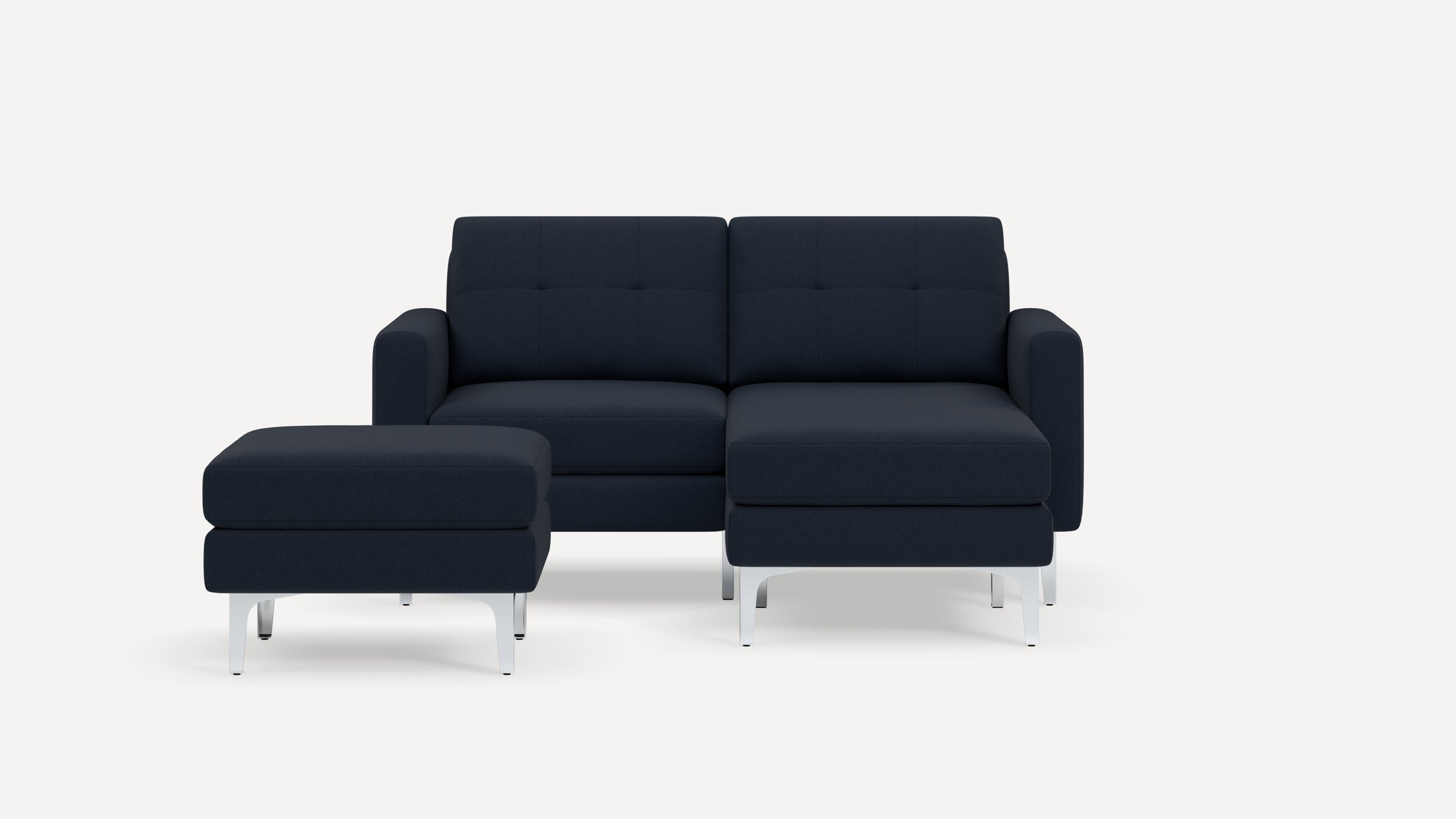 Modern navy blue fabric sectional sofa with matching ottoman, tufted cushions, and sleek silver metal legs against white background.
