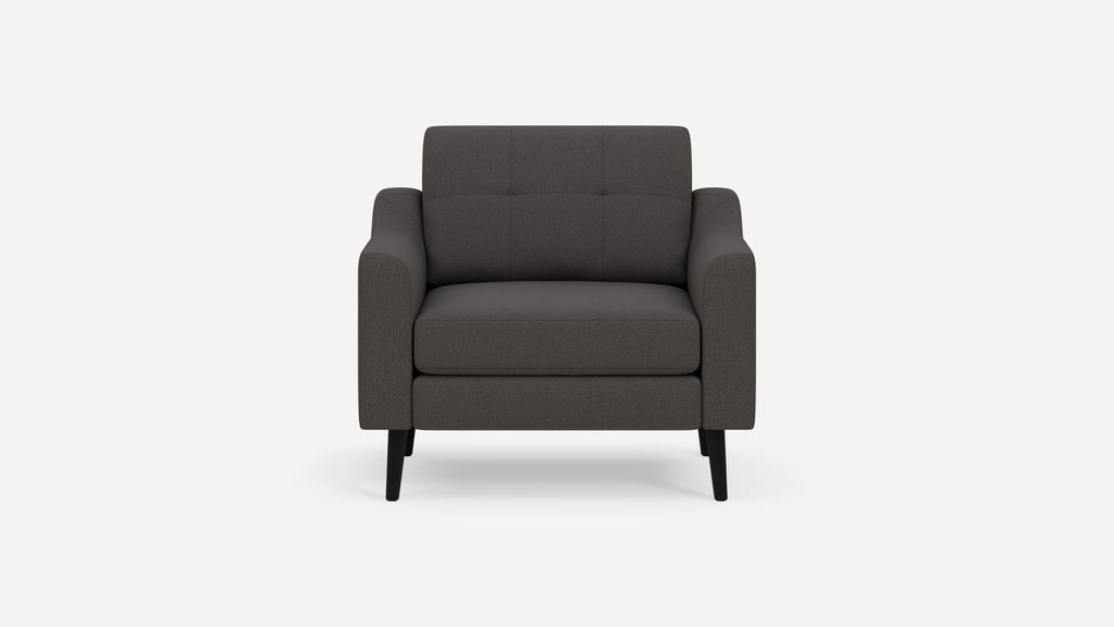 Modern dark gray fabric armchair with padded seat and backrest, featuring tufted detailing and black tapered legs.