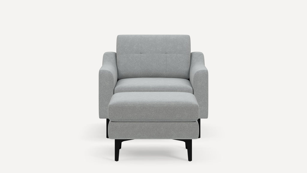 Front view of a modern light gray upholstered armchair with angled black legs and a matching ottoman.
