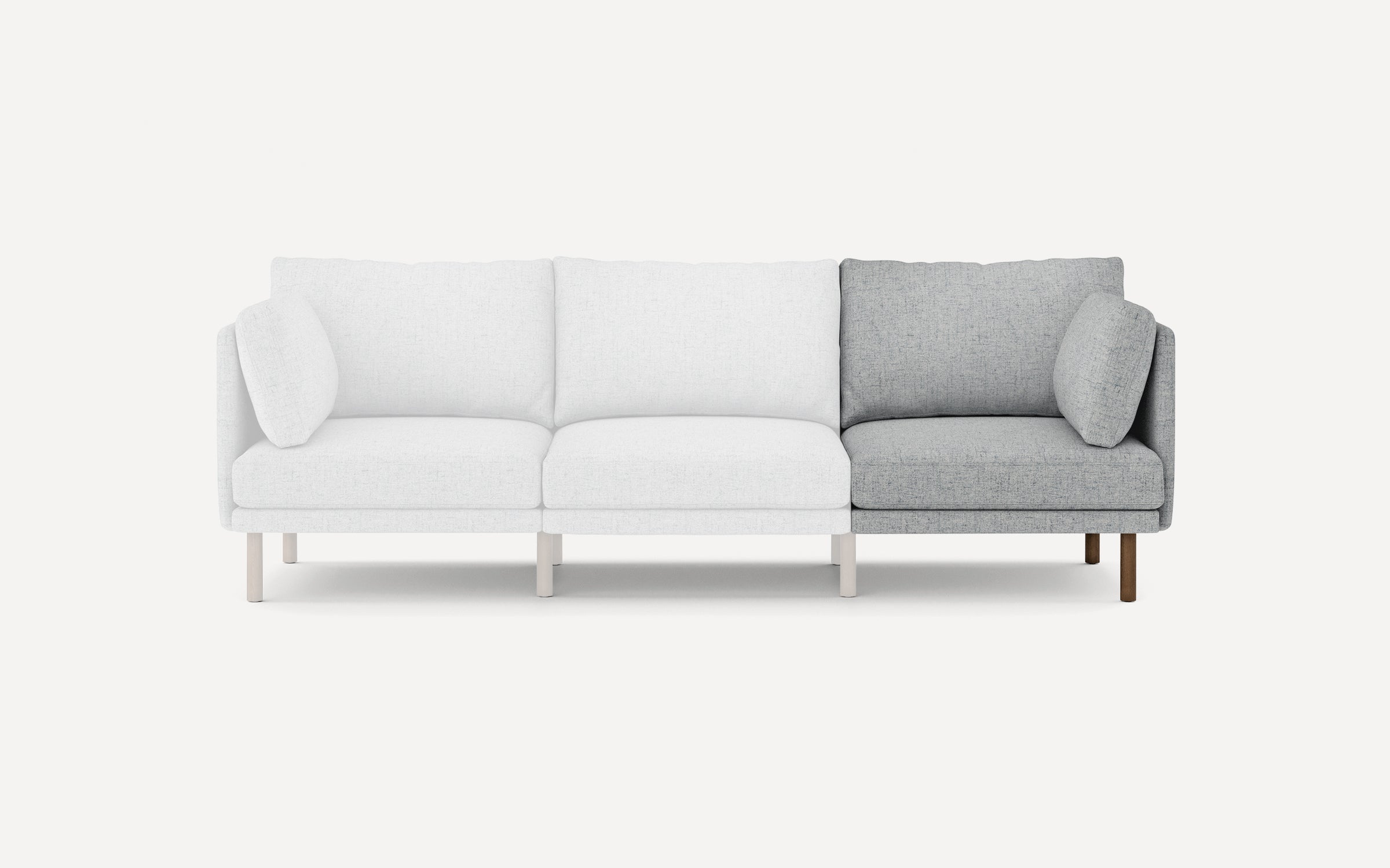 Modern three-seater sofa with two white seats and one light gray seat, featuring matching cushions and wooden legs.
