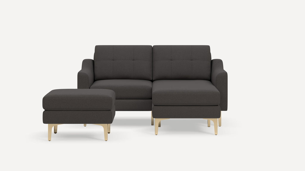 Dark gray modern sectional sofa with tufted back cushions and matching ottoman, featuring light wooden legs on a white background.