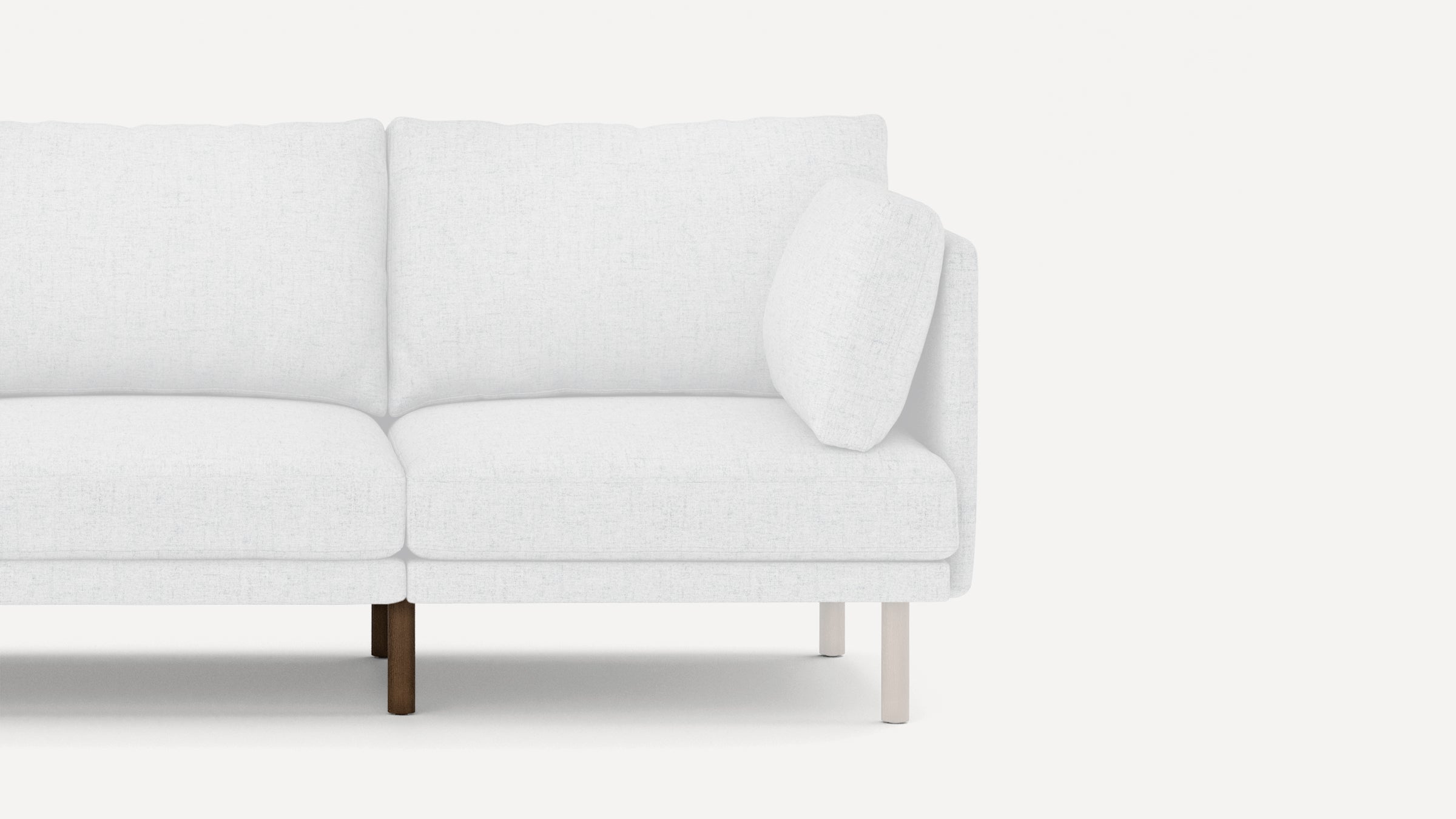 Modern white fabric sofa with clean lines, wooden legs, and a loose side cushion, shown from a partial side view.