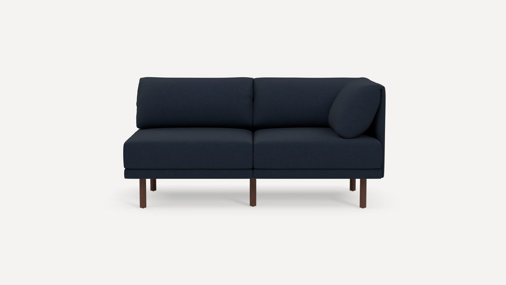 Modern navy blue two-seater sofa with wooden legs and a rounded cushion on one side, set against a plain background.