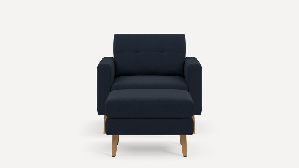 Front view of a modern navy blue armchair with matching ottoman, featuring wooden legs and cushioned armrests.