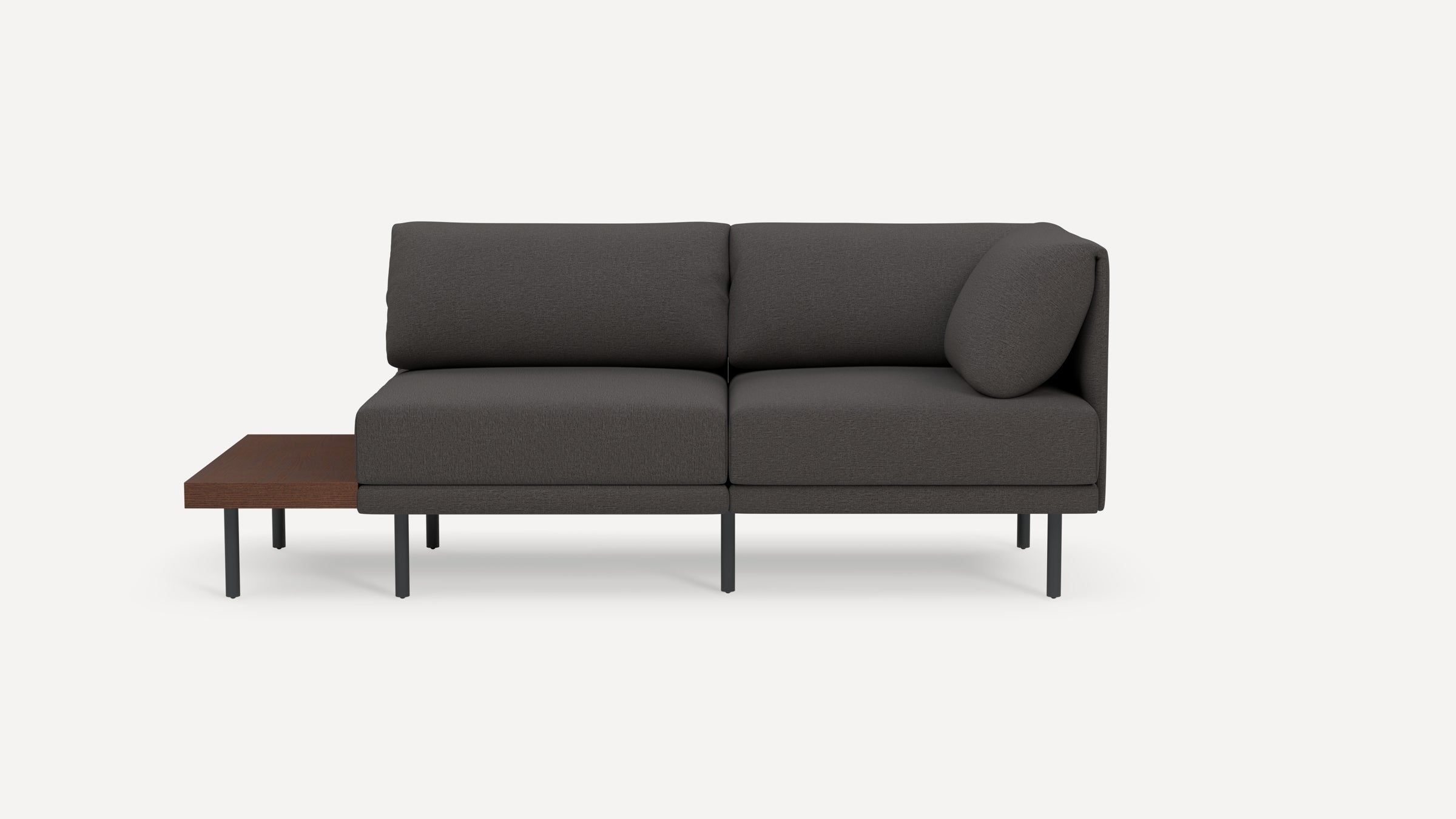 Modern dark gray two-seater sofa with cushioned backrest, a round pillow on one side, and an attached wooden side table with metal legs.