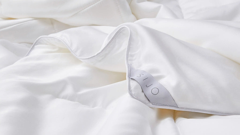 a close up of a white bed with a white comforter