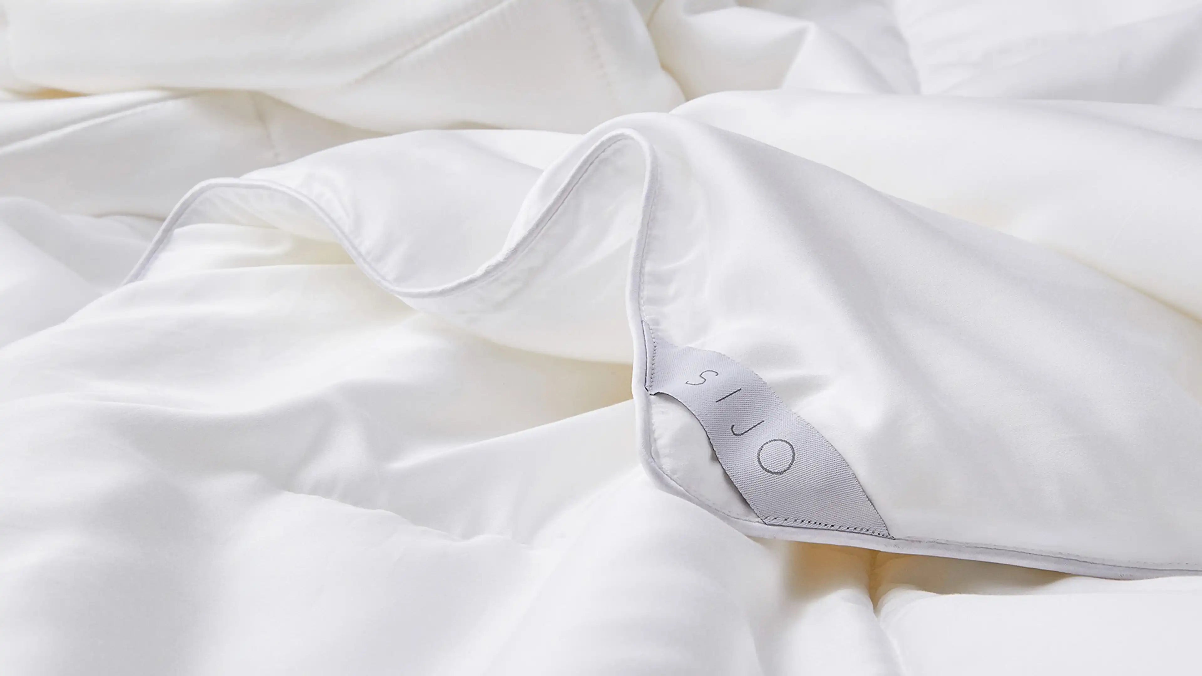 a close up of a white bed with a white comforter