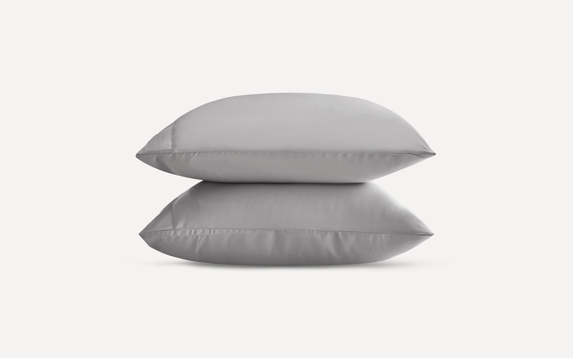 Two neatly stacked gray pillows with smooth fabric and clean seams on a plain white background.