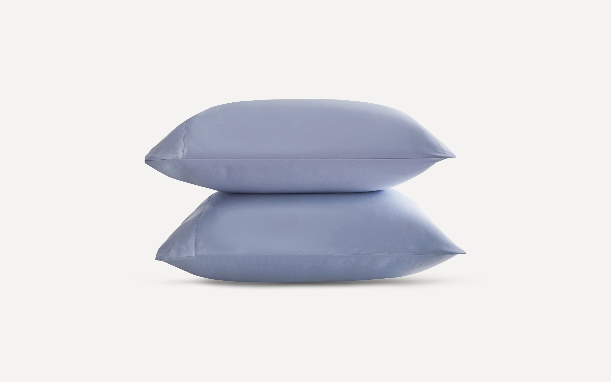Two neatly stacked light blue pillows with smooth fabric, displayed against a plain white background.