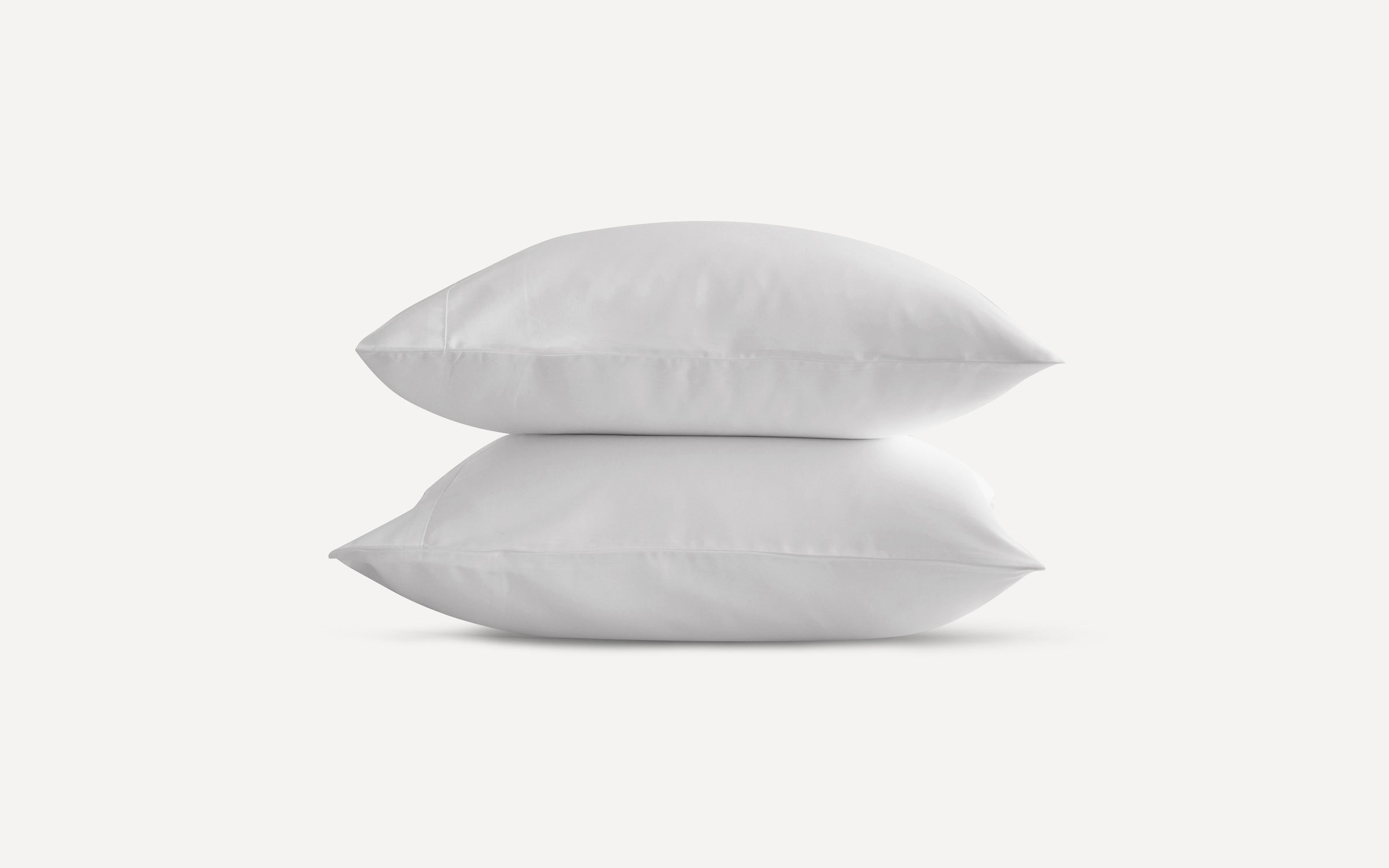 Two plain white pillows stacked neatly against a light background.
