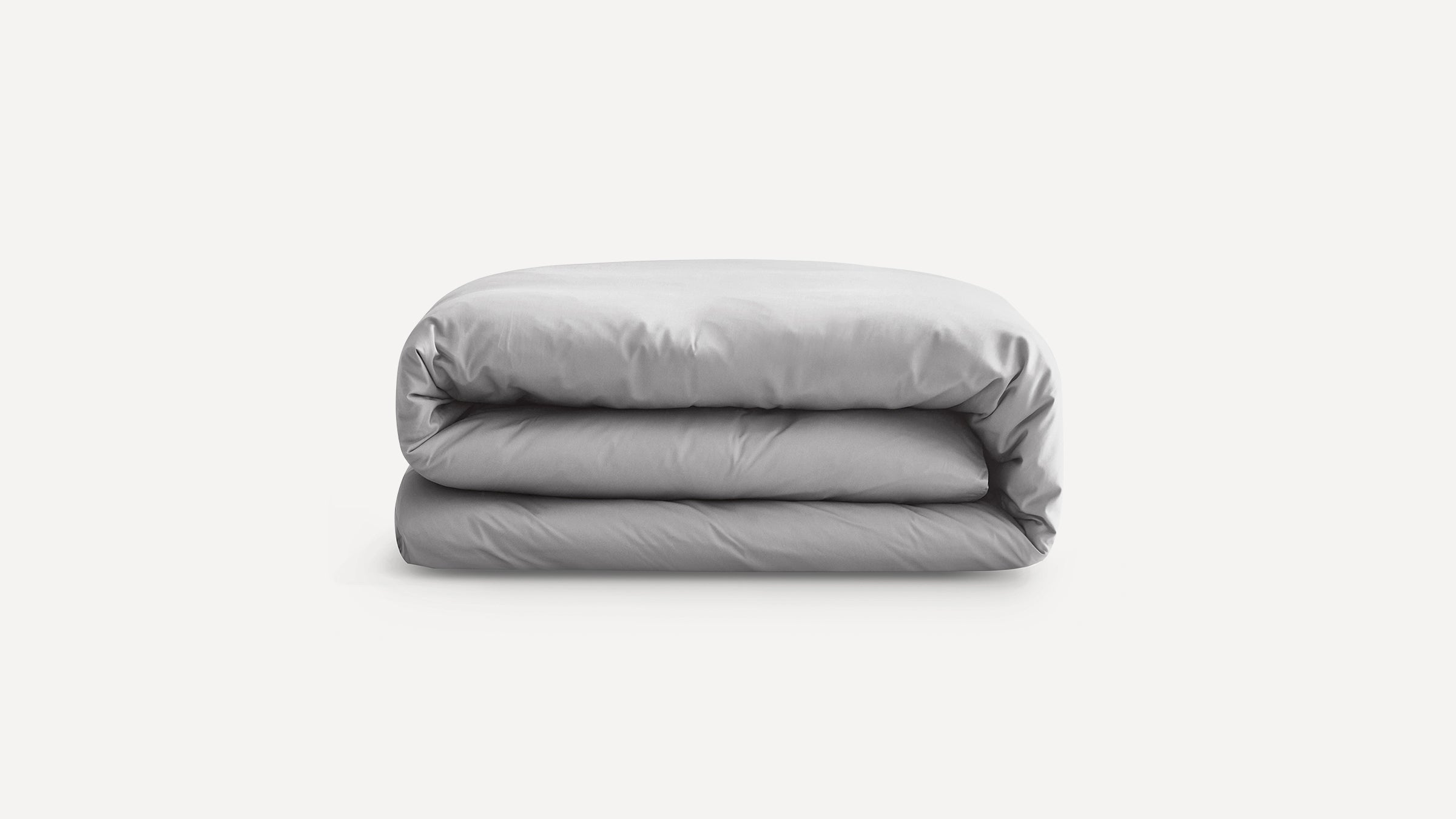 Folded light gray comforter or duvet against a plain white background, neatly packed and smooth.