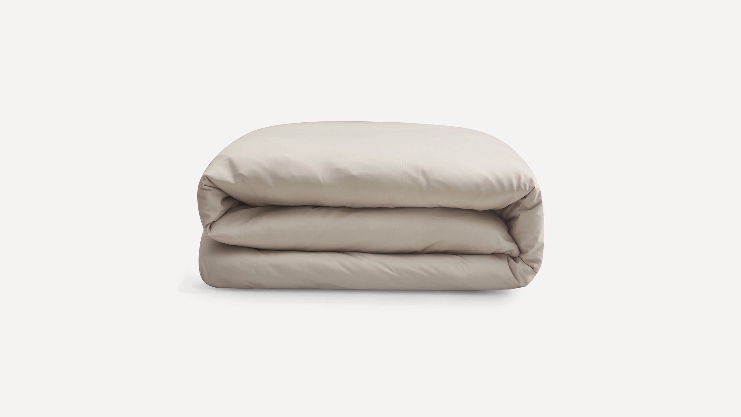Light beige folded duvet or comforter with a smooth, soft fabric texture on a white background.