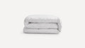 Neatly folded, plain white duvet or comforter on a white background, showcasing its soft and plush texture.